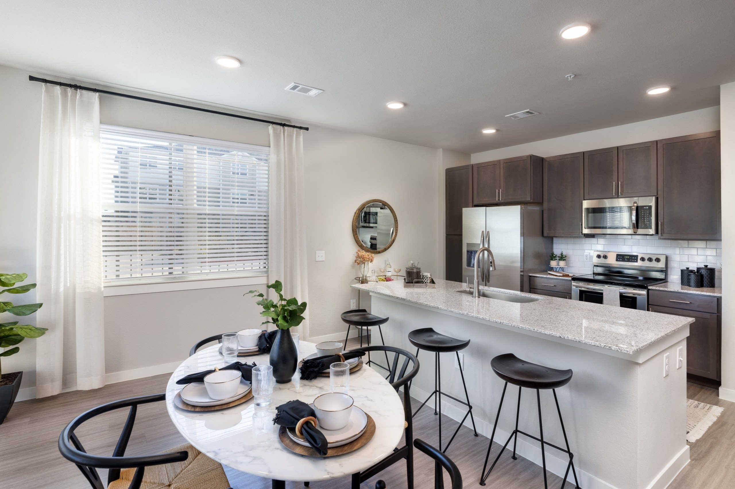 an open kitchen and dining area with a marble counter top and a table with chairs